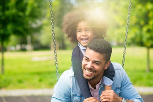 father and daughter on a swing at the oakfield playground space