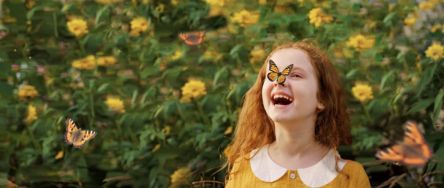 girl with a butterfly on her nose in a flower garden