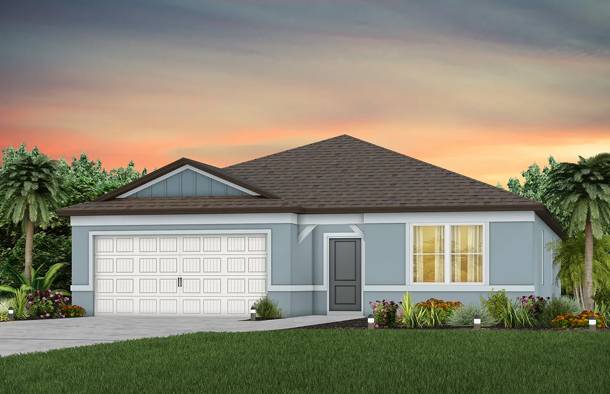 Single-story blue house with a gray roof, white garage door, and front door. Large windows are lit from inside. Lush green lawn, some flowers, and palm trees. The sky is colorful with sunset hues.