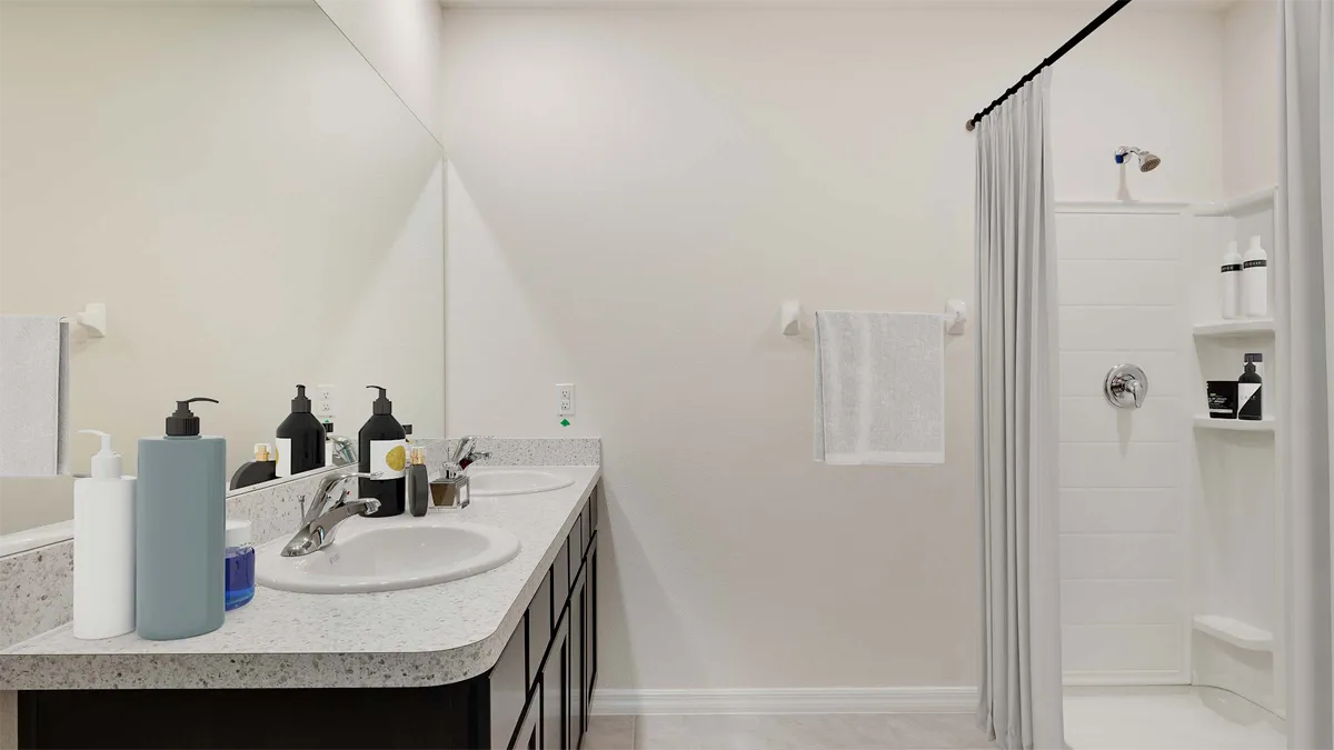 Modern bathroom with double sinks, dark cabinets, soap dispensers, a towel on a rack, and a white shower with shelving and a gray curtain. The room has light walls and a clean, minimal look.