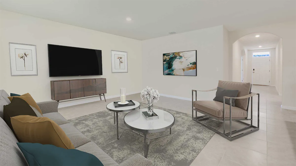 A modern living room with a gray sofa, armchair, two round coffee tables, decorative art on the walls, a large TV, and neutral-colored decor. Light tiles cover the floor and an entryway is visible in the background.