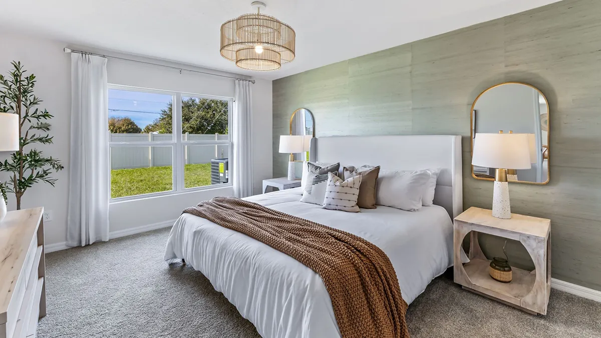 Modern bedroom with a large bed, white bedding, brown knit throw, two nightstands with lamps, arched mirrors, a large window with curtains, green accent wall, and a potted plant in the corner.