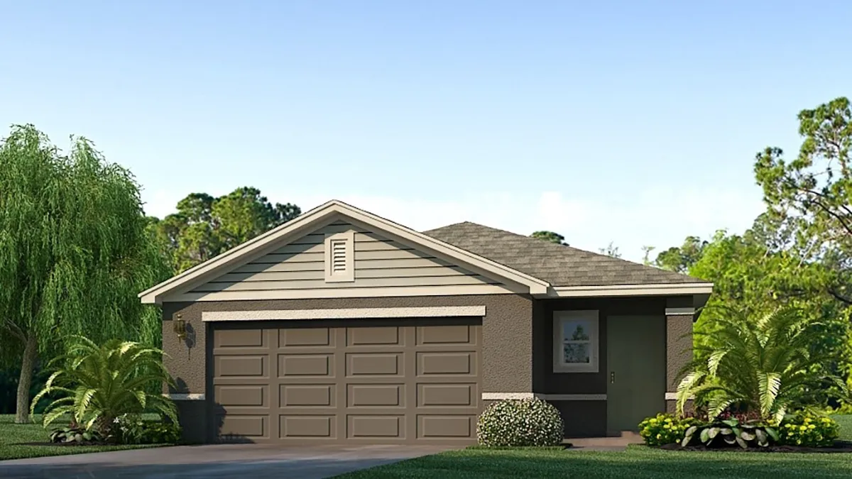 A single-story suburban house with a double garage, gray siding, and brown trim, surrounded by green shrubs, small trees, and a well-maintained lawn under a clear blue sky.