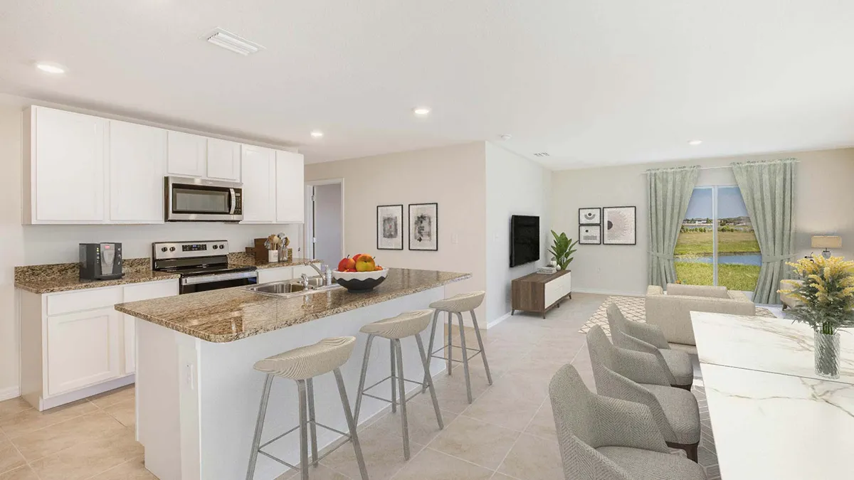 Modern open-concept kitchen and living area with white cabinets, granite countertops, barstools, a dining table, and large windows showing a scenic view of a lake and greenery.