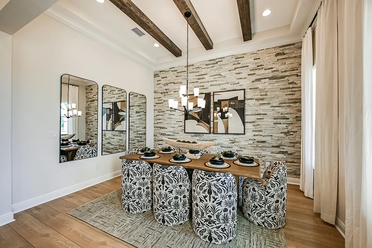A modern dining room with a wooden table set for six, matching floral-patterned chairs, two large wall mirrors, a contemporary chandelier, and a textured stone accent wall with abstract artwork.