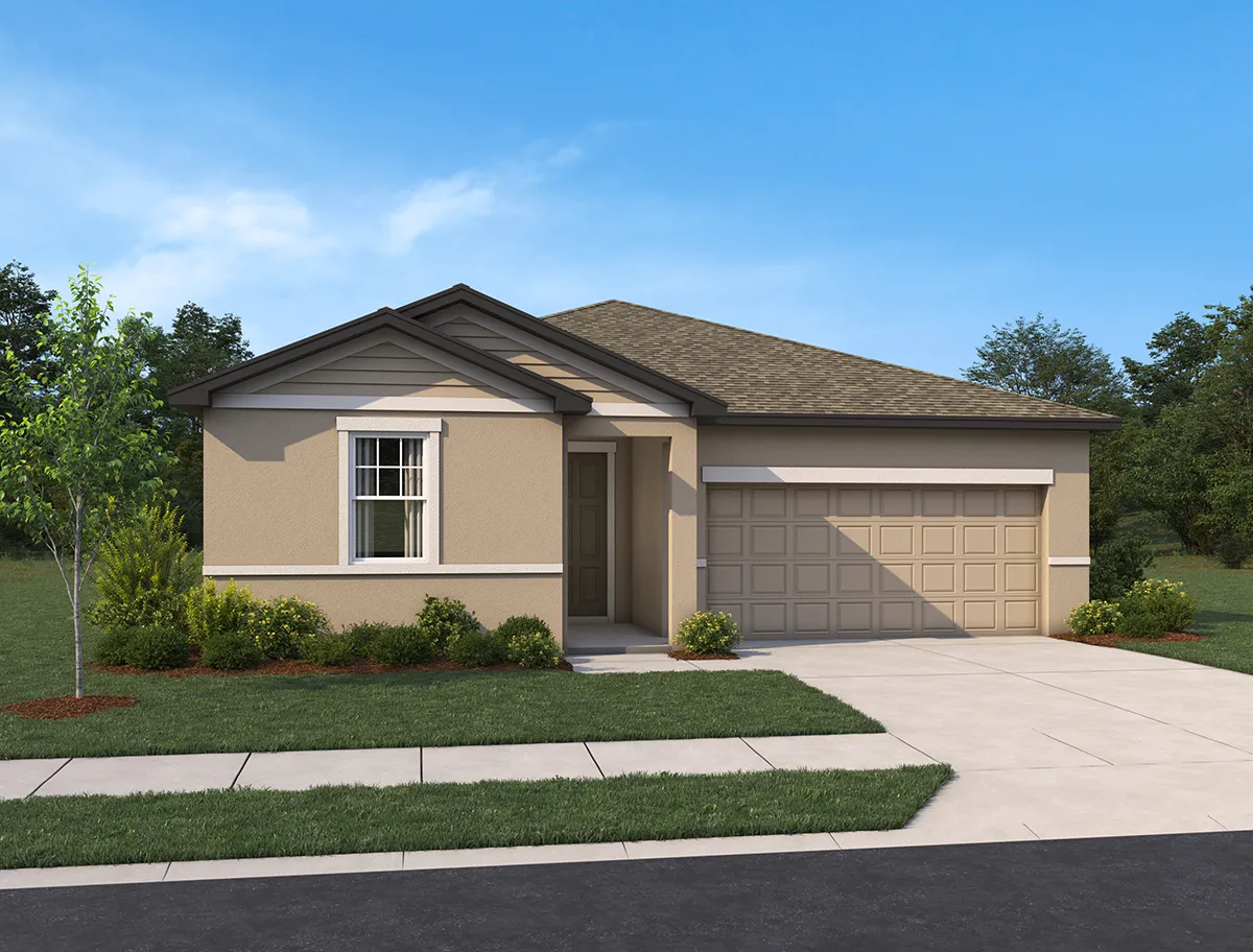 Single-story beige house with a two-car garage, gable roof, and a small covered entry. The front yard has neatly trimmed grass, shrubs, and a young tree. A driveway leads to the garage, and the sky is clear.