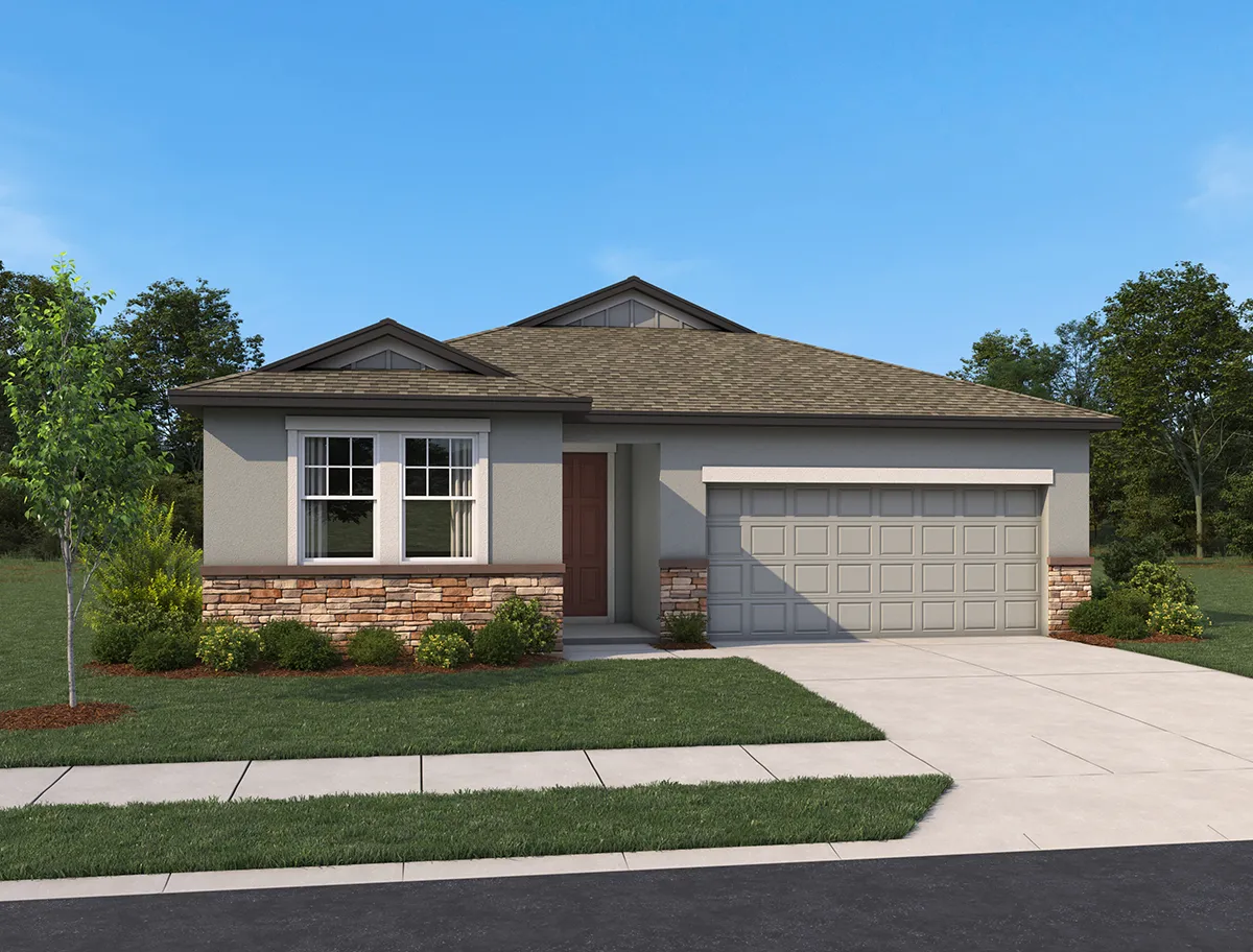 Single-story suburban house with a gray exterior, stone accents, a two-car garage, front lawn, small shrubs, and a tree. The house sits under a clear blue sky with trees in the background.