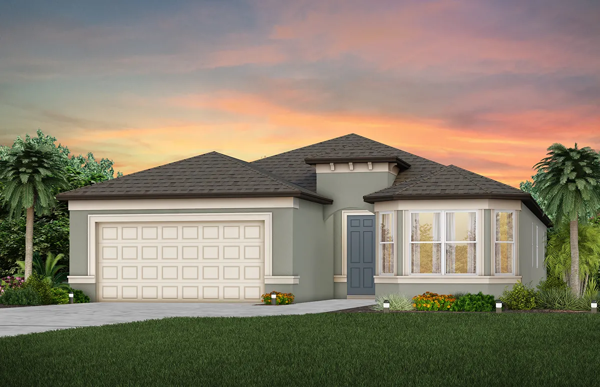 A modern single-story house with a two-car garage, gray walls, blue front door, and large bay windows, surrounded by green lawn, plants, and palm trees at sunset.