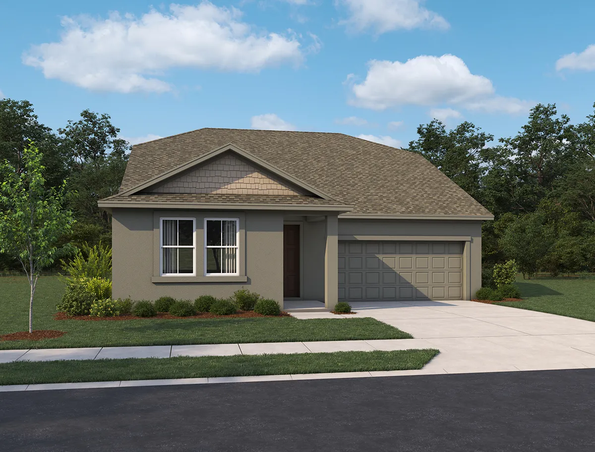 Single-story house with a gray exterior, two-car garage, and front lawn with small shrubs and a young tree, set against a backdrop of trees and a blue sky with scattered clouds.