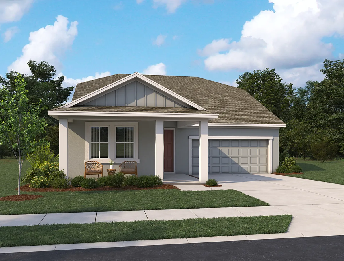 Single-story suburban house with a covered front porch, two chairs, attached two-car garage, manicured lawn, shrubs, and trees in the background under a partly cloudy sky.