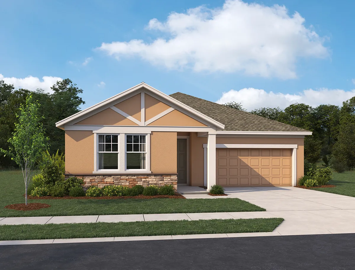 Single-story suburban house with tan walls, stone accents, a gabled roof, and a two-car garage. The front yard has neatly trimmed bushes, a small tree, and a clear blue sky in the background.